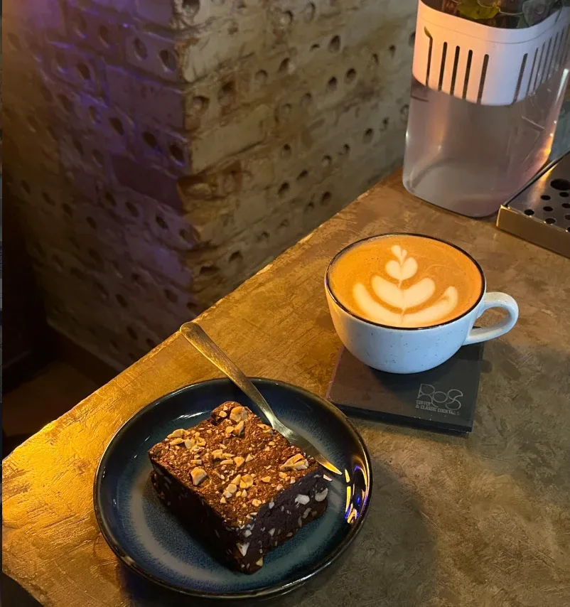 Latte com desenho na espuma e brownie com castanhas no balcão do ROS